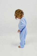 Child wearing a light blue long sleeve jumpsuit on a white background