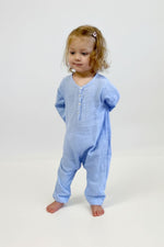 Child wearing a light blue jumpsuit with long sleeves against a white background