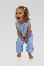 Child wearing a light blue sleeveless jumpsuit and laughing on a white background