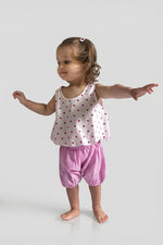 Child wearing pink bubble shorts with a polka dot top on a white background