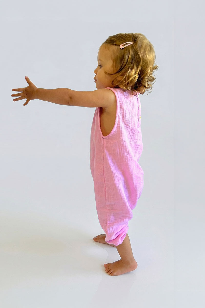 Child wearing a pink sleeveless jumpsuit on a white background
