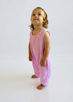 Child wearing a pink sleeveless jumpsuit on a white background