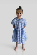 Young girl wearing a Gingham blue dress on a white background