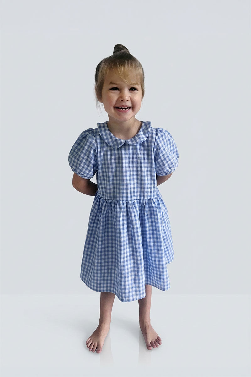 Young girl wearing a Gingham blue dress on a white background
