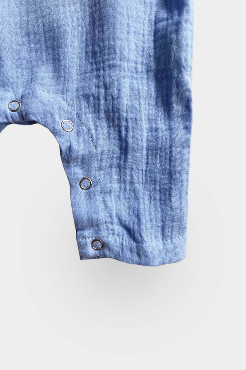 Long sleeve blue jumpsuit leg snaps on grey background