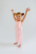 Child wearing a light pink sleeveless jumpsuit against a plain background