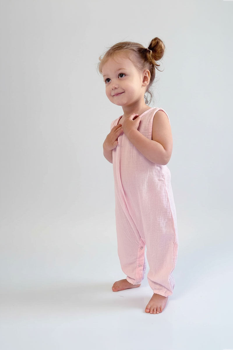 Child wearing a light pink sleeveless jumpsuit on a white background