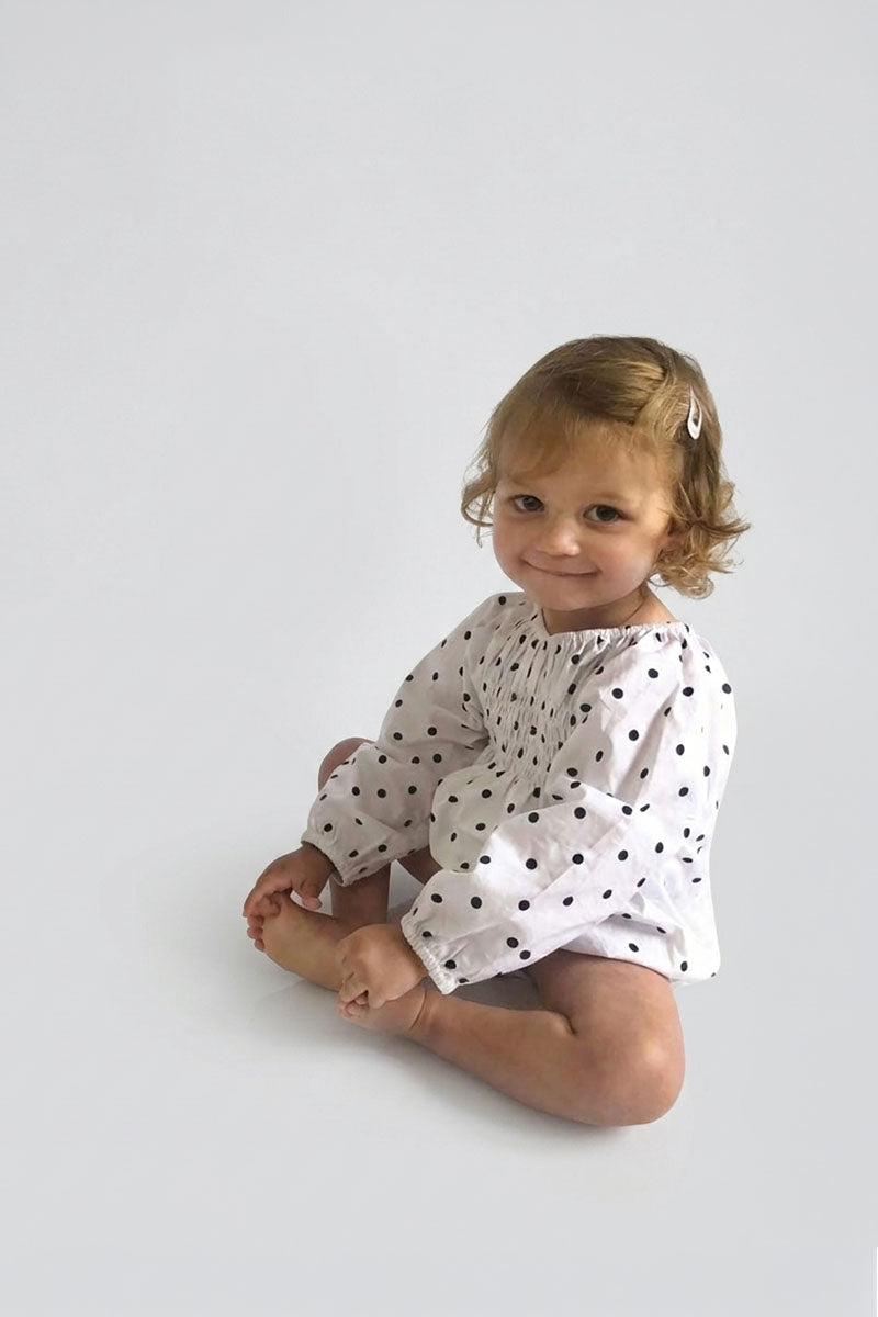 Child wearing a Polka Dot long sleeve romper on a light grey background