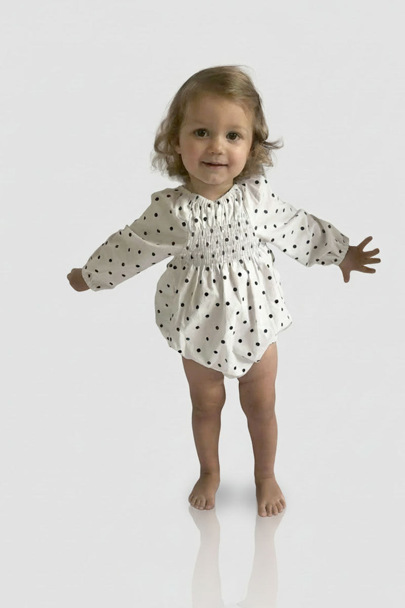Child wearing a Long Sleeved Polka Dot Romper on a white background