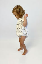 Child wearing a Polka Dot Smocked Romper with short sleeve on a white background