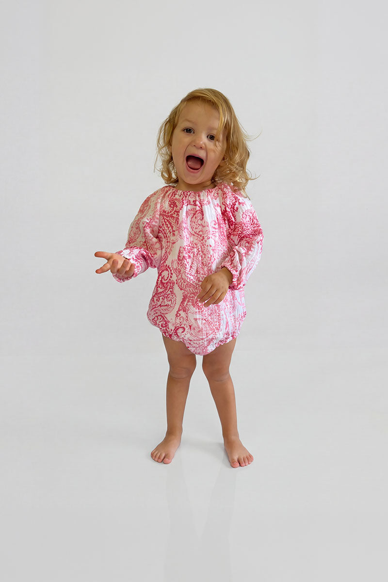 Child wearing a Red Paisley Romper with long sleeves on a white background