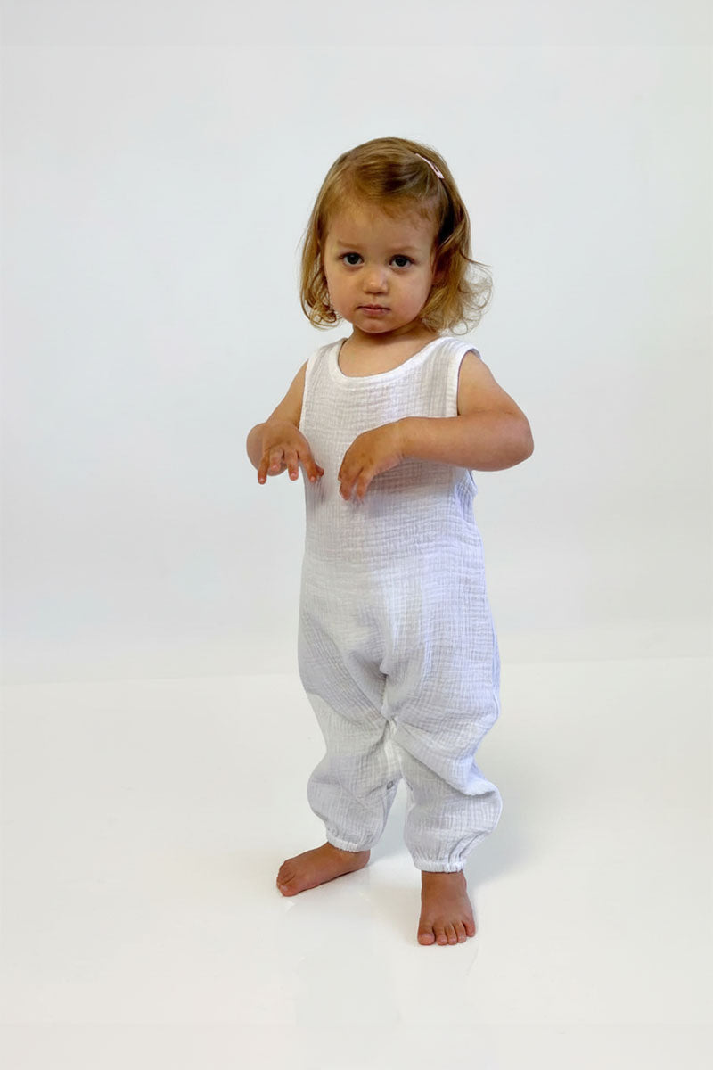 Child wearing a white sleeveless jumpsuit on a white background