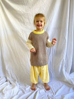 Young girl stood up smiling wearing our Anytime Knit in Desert colour