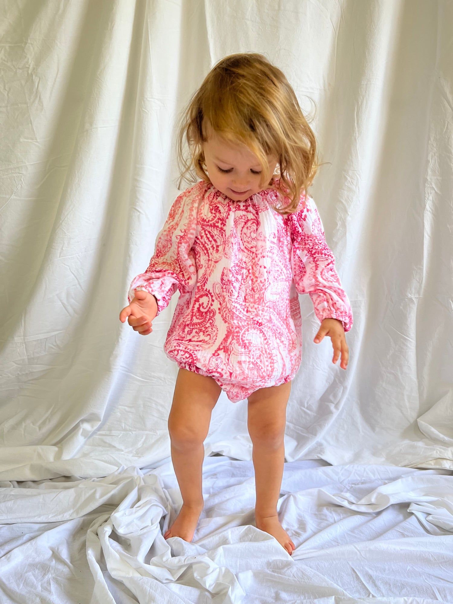 Young child wearing a Long Sleeve Romper in Paisley Red colour