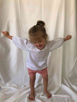 Young girl stood up smiling wearing our Bubble Sleeve Blouse in Polka Dot
