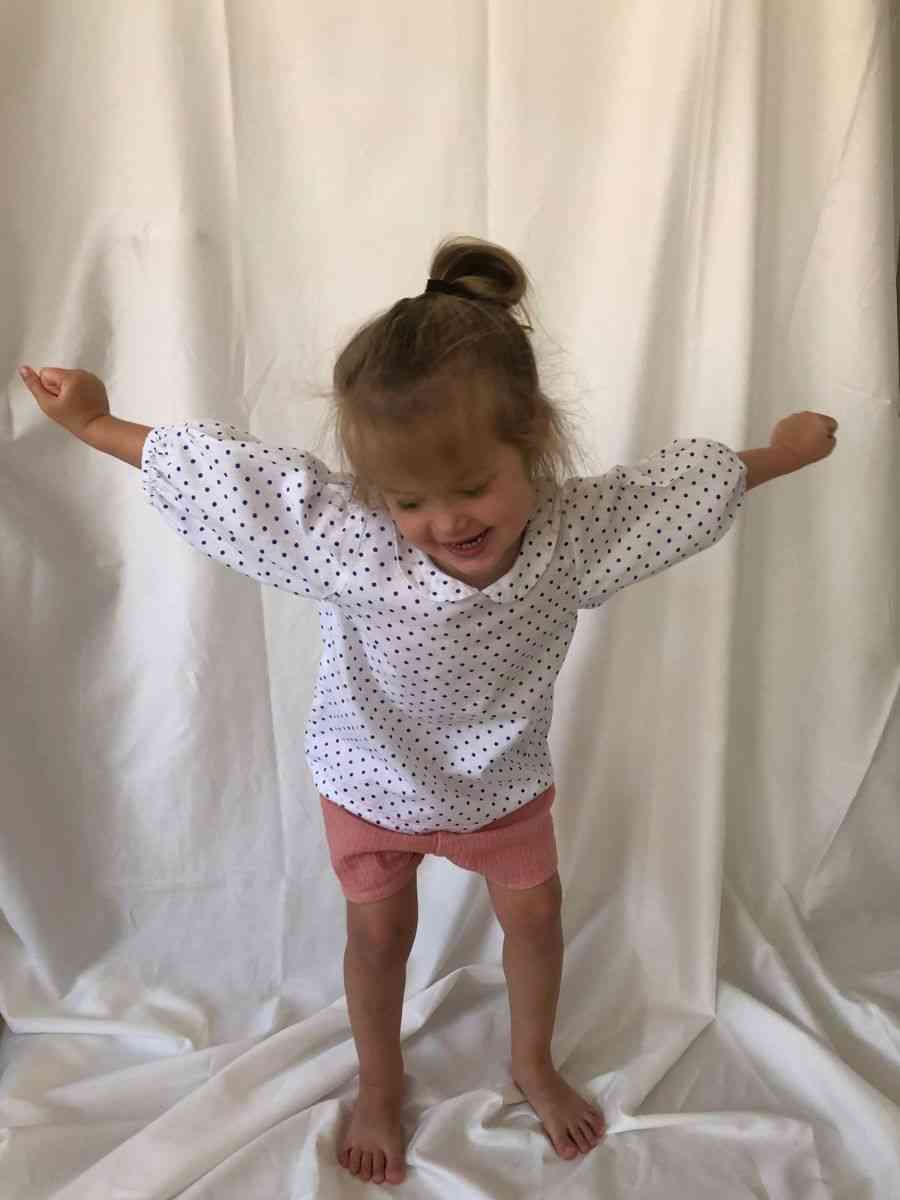 Young girl stood up smiling wearing our Bubble Sleeve Blouse in Polka Dot