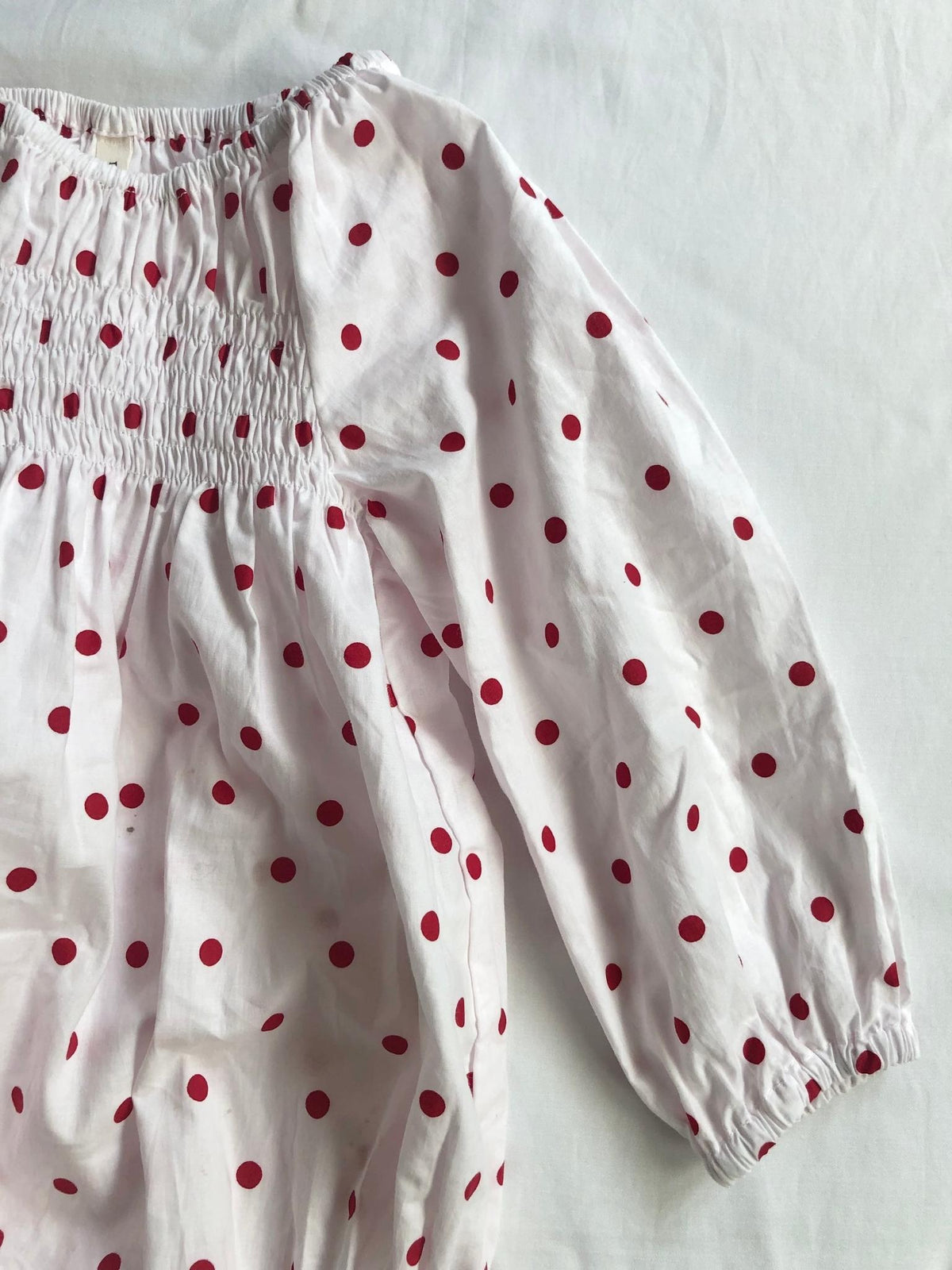 Romper smocked with long sleeves in red polka dot arm view
